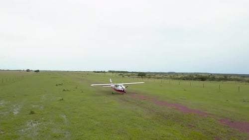 Drone, aerial shot of a light aircraft landing on a dirt track.
