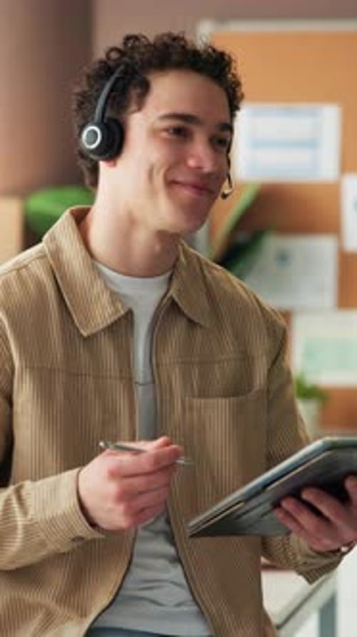 Man Smiling and Using Tablet Wearing Headset Indoors
