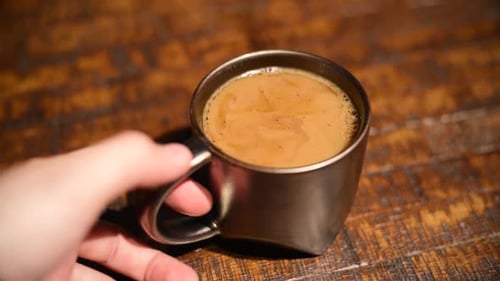 Hand Lifts Coffee Mug From Wooden Table
