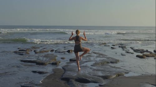 Back View of the Sporty Caucasian Blonde Girl Practicing Vrksasana Pose Outside on the Beach