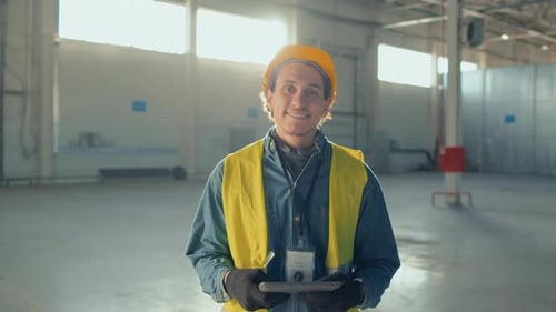 Smiling Worker Holds Tablet in Warehouse Interior