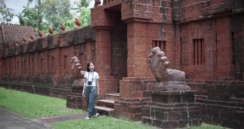 An Asian female tourist walks around the temple grounds and takes photos.