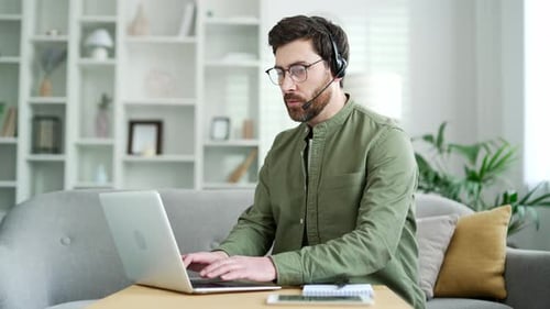 Man Talking on Laptop with Headset at Home