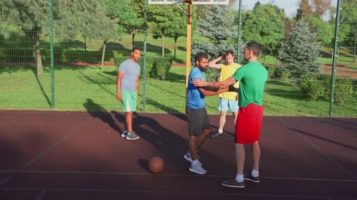Jogador de basquete masculino estendendo a mão para levantar o oponente negro caído