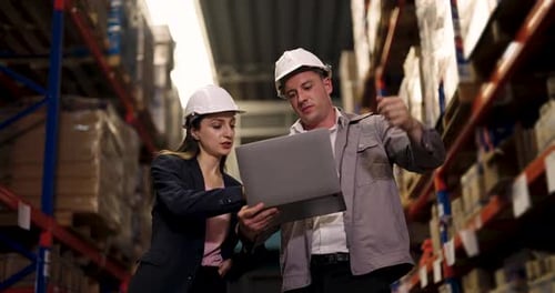 female logistics manager and male warehouse staff analyzing shelf inventory while standing near