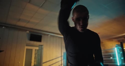 Boxeador dinámico en acción: movimientos rápidos en un entorno de gimnasio oscuro