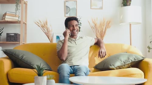 Young Man Talking on Smartphone on Couch Indoors