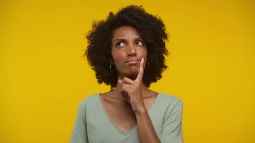 Woman Thinking with Finger on Chin, Yellow Backdrop
