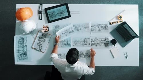 Blick von oben auf den Architekten und Ingenieur, der den Gebäudeplan auf den Tisch legt. Ernährung.