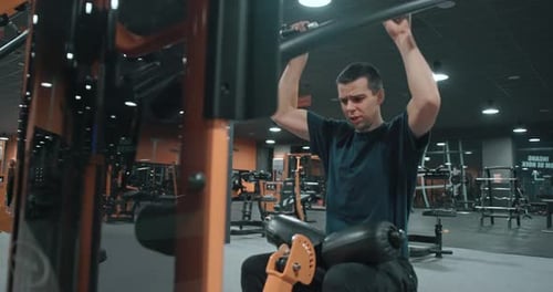 20s man working out led pulldowns on indoor fitness gym slow motion