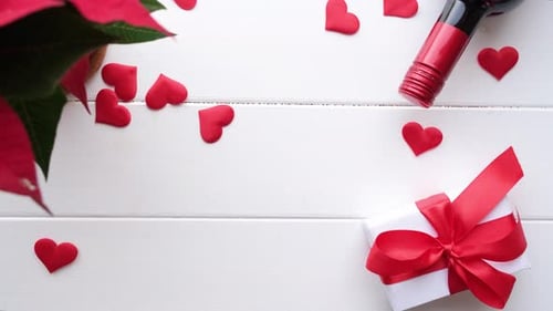 heart shaped confetti falling on white wooden table decorated for valentines day