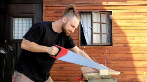 Man sawing wood with hand saw