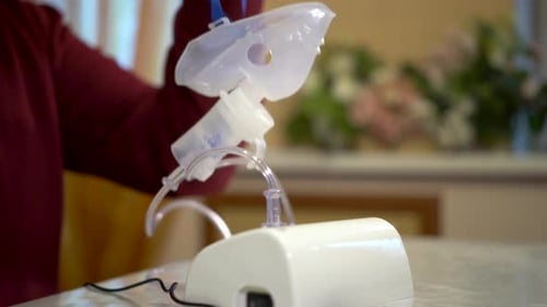 The Inhaler Device is on the Table The Man Takes the Mask and Breathes Through It