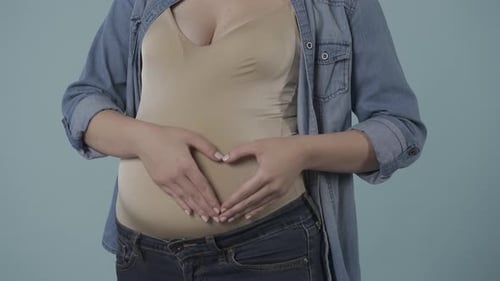 Une femme enceinte caresse son ventre gonflé avec amour et tendresse montre un signe cardiaque qui la met