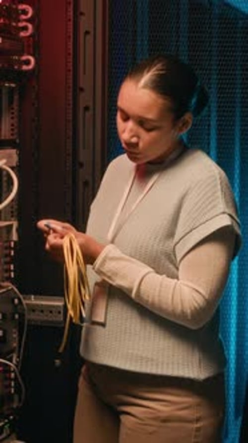 Woman Inspecting Cables in a Dark Server Room
