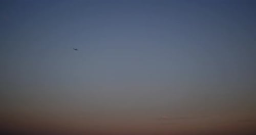 Silhouette of a plane passing over deep blue evening sky.