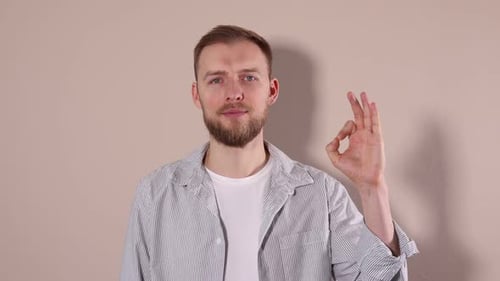 Glücklicher Mann zeigt gute Geste auf beigem Hintergrund