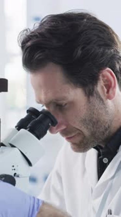 Scientist, laboratory and man with microscope for sample analysis, medical research and chemistry