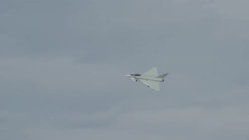 Fighter jet flying against a cloudy blue sky