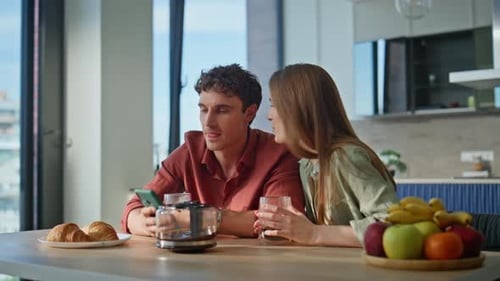 Happy Couple Looking at Phone in Sunny Kitchen