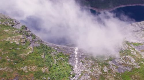 aerial view of norwegian fjords and waterfall through clouds