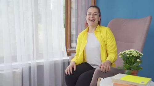 Woman Smiling and Clapping in Armchair
