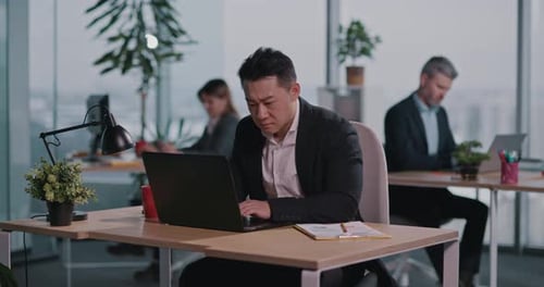 Workers typing on laptops in an open plan office