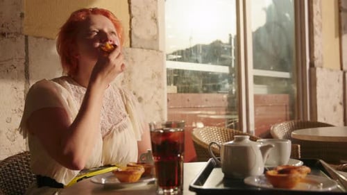 Woman Eating Pastry at Outdoor Cafe at Sunset
