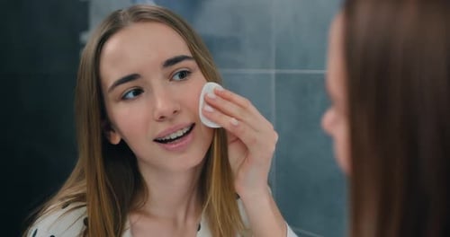 Close-up of young beautiful woman in pajamas with clean skin stands in bathroom