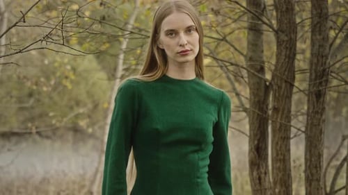 Model posing wearing green dress in autumn forest