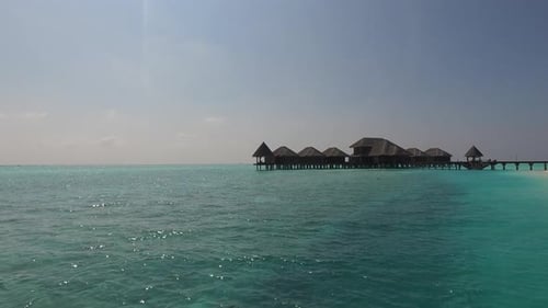 Águas azul-turquesa cercam bangalôs tropicais em uma ilha paradisíaca das Maldivas