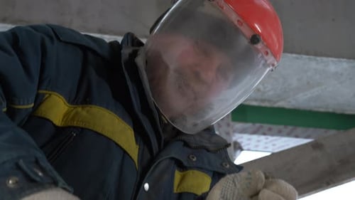 Building a house. A man in a special uniform with equipment works with metal