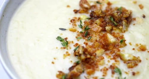 Cauliflower soup in close up. Bowl of healthy vegetable soup rotating. Plant based vegan food. High