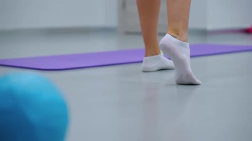Balancing on One Foot in Socks with Raised Heel Near Balloon in Gym