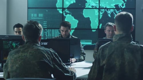 Group of Military IT Professionals in Monitoring Room Filled with Displays on Military Base