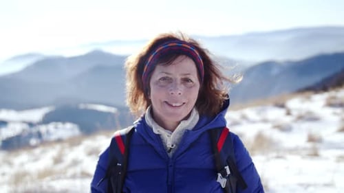 Senior woman hiker stands in snow covered slovakia winter landscape looking at camera