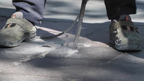 Worker Repairs Pavement in Busy Urban Area