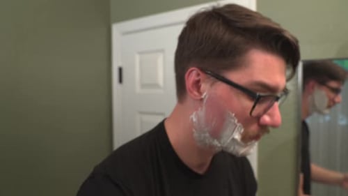 Adult Man Shaving in Bathroom Mirror Close Up