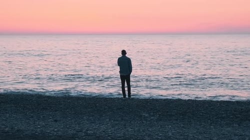 Lonely Man Standing on the Sea Coast at Sunset Male with Mental Problems on the Beach By the Ocean