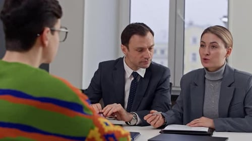 Especialistas en recursos humanos verifican el CV y hablan con un joven candidato durante la entrevista