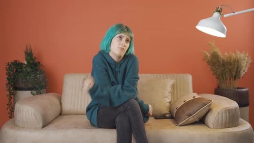 Woman with Teal Hair Sits Sad on Couch