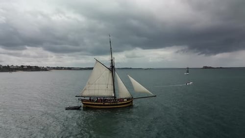Bateau en bois Le Renard Robert Surcouf sur mer avec ciel nuageux. Drone aérien