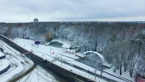 Transport road in the city near the big park. Snowy urban panorama in winter season. Aerial view.