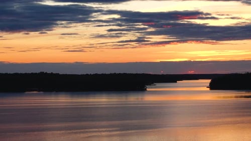 Sunset paints the sky in vibrant. The sun descends over the sea, illuminating the water and islands.