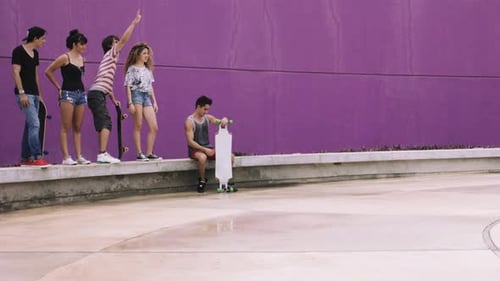 Teenage girl enjoying skateboarding and giving high-five to friends on street