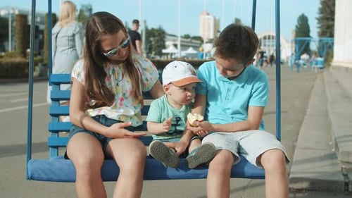 Adorable Three Siblings Riding on Swing in Amusement Park. Cute Two Brothers
