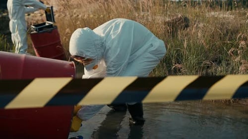 Scientists Examining Red Barrel in Environmental Protective Suits
