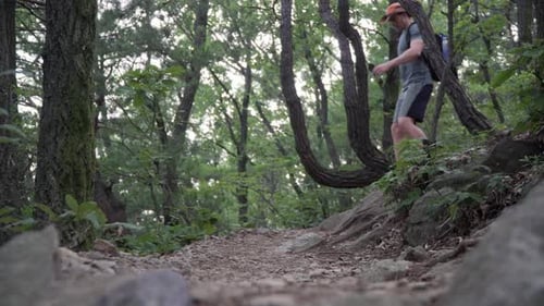 Low angle view of male swet tired hiker walking down from the mountain trail
