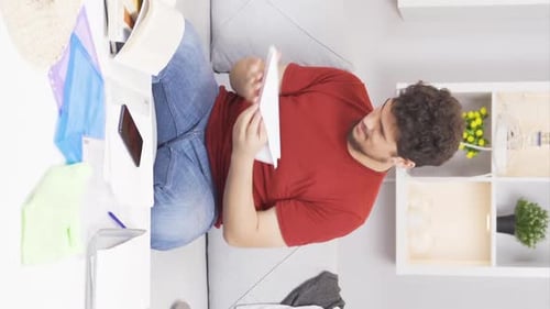 Young Man Reading Letter on Couch Indoors