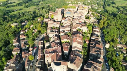 Drone aerial view in France countryside small old medieval brick town on a mountain top surrounded b